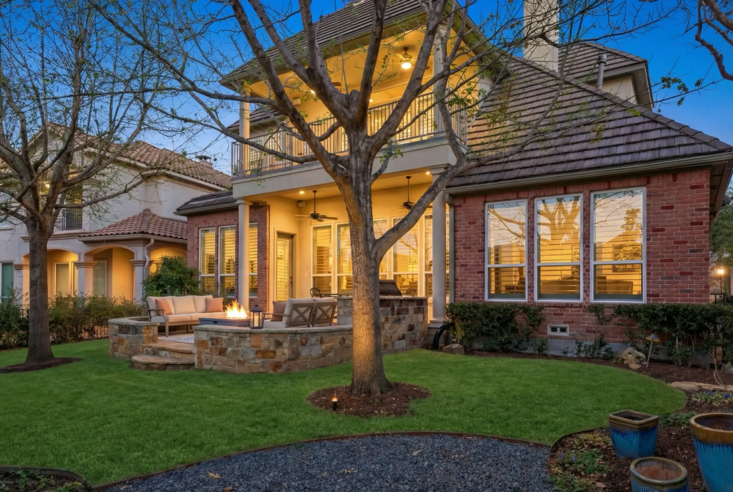 Resort-quality backyard with stone patio, covered porch, and mature trees
